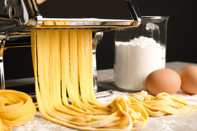 Pasta maker machine with dough and products on grey table, closeup