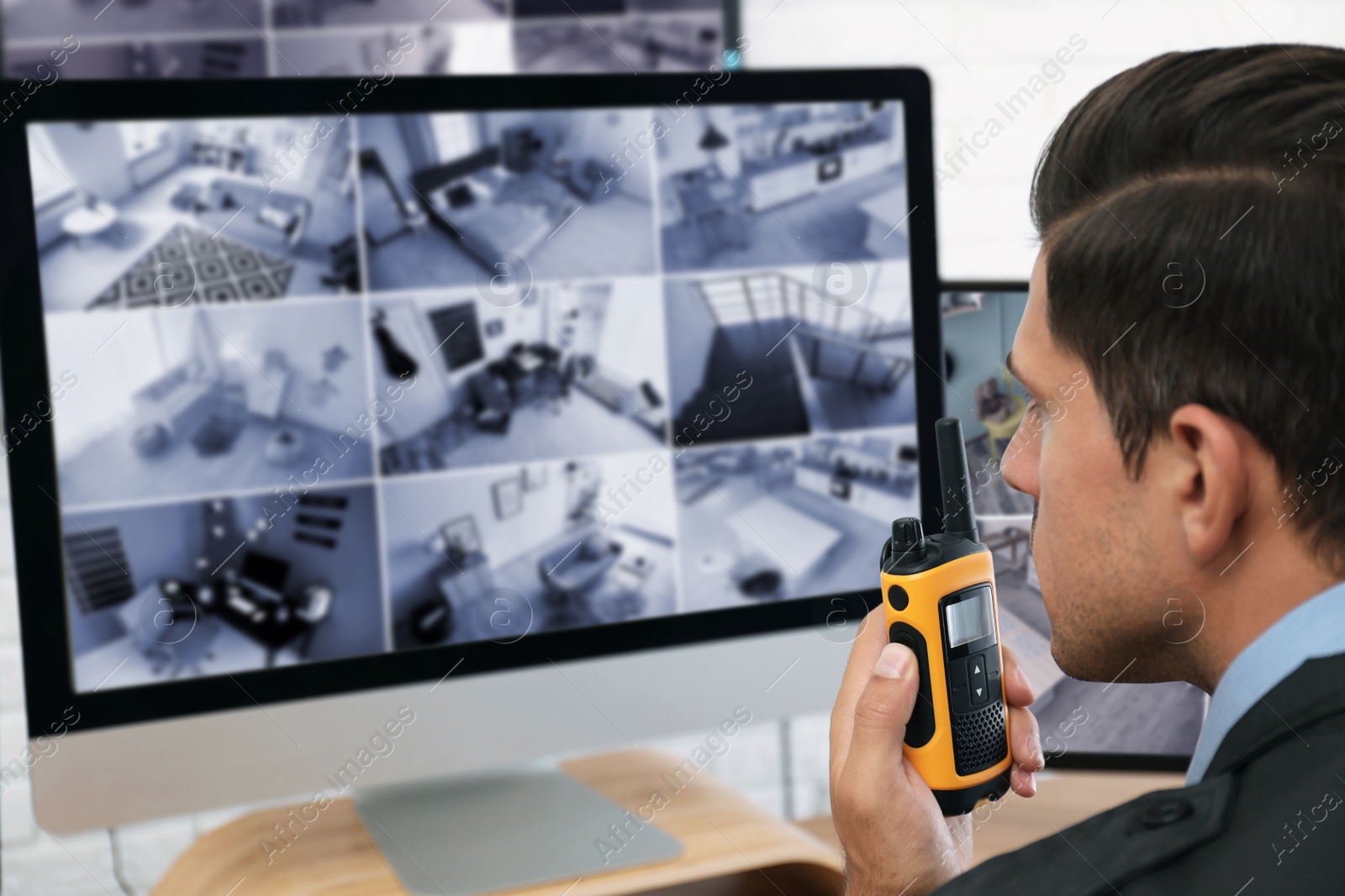 Photo of Male security guard with portable transmitter near monitors at workplace, closeup