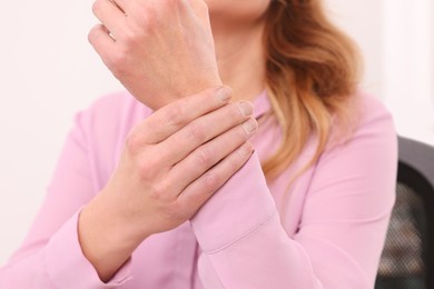 Photo of Woman suffering from pain in wrist indoors, closeup. Arthritis symptoms