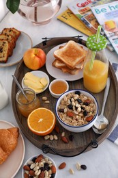 Tray with tasty breakfast on white table, above view