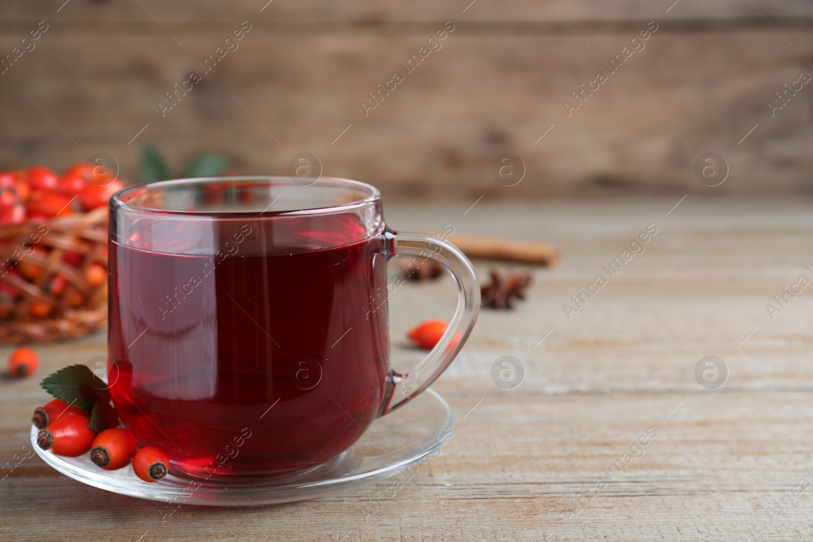 Photo of Aromatic rose hip tea and fresh berries on wooden table, space for text