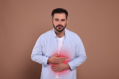 Man suffering from stomach pain on brown background