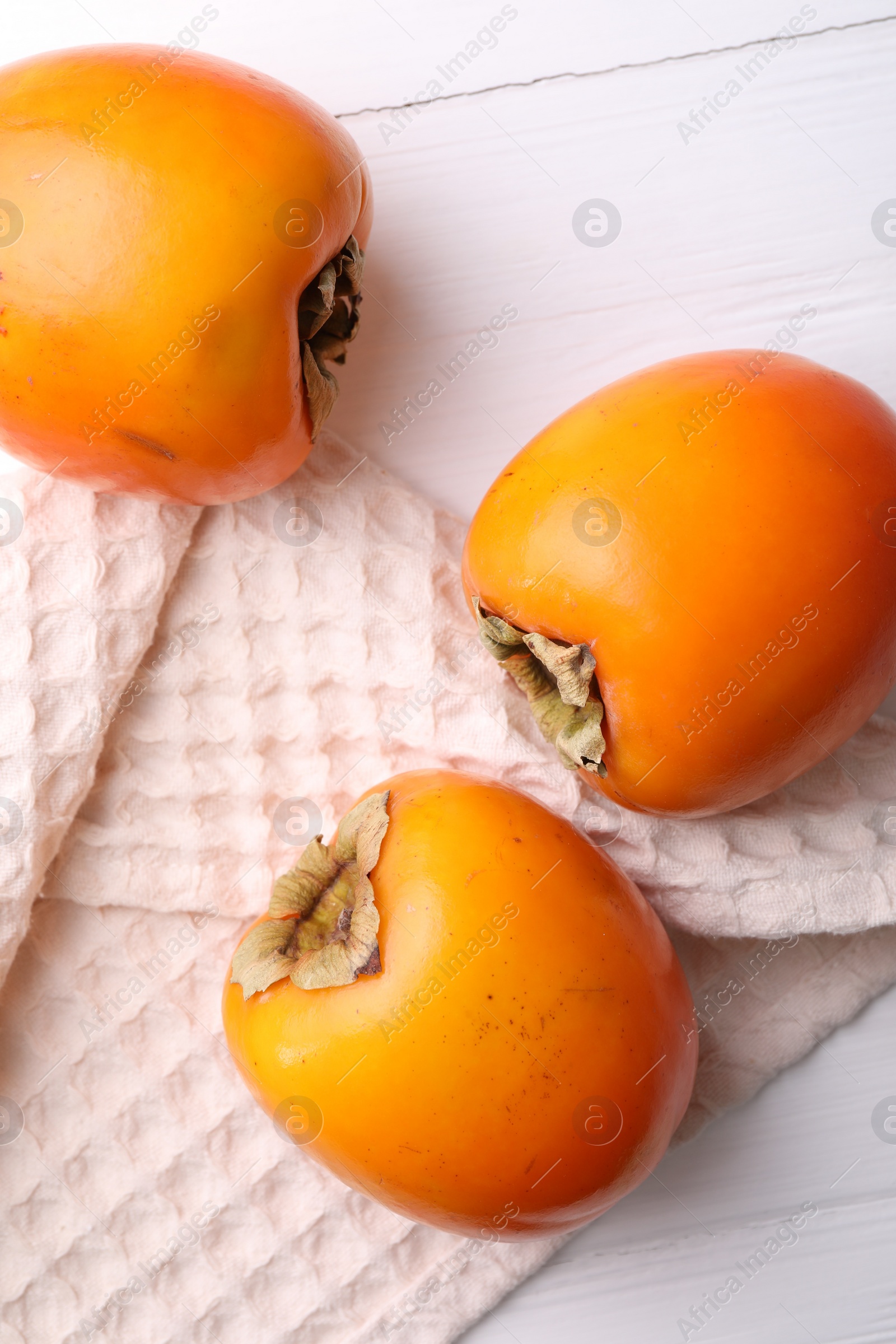 Photo of Delicious ripe persimmons on white wooden table, top view