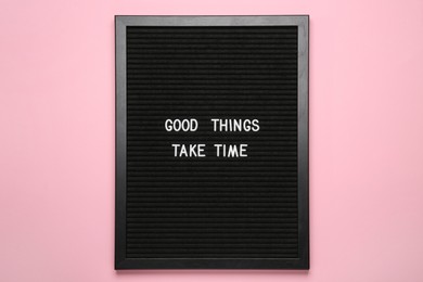 Photo of Black letter board with motivational quote Good Things Take Time on pink background, top view