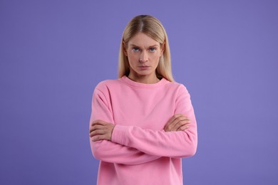 Photo of Resentful woman with crossed arms on purple background