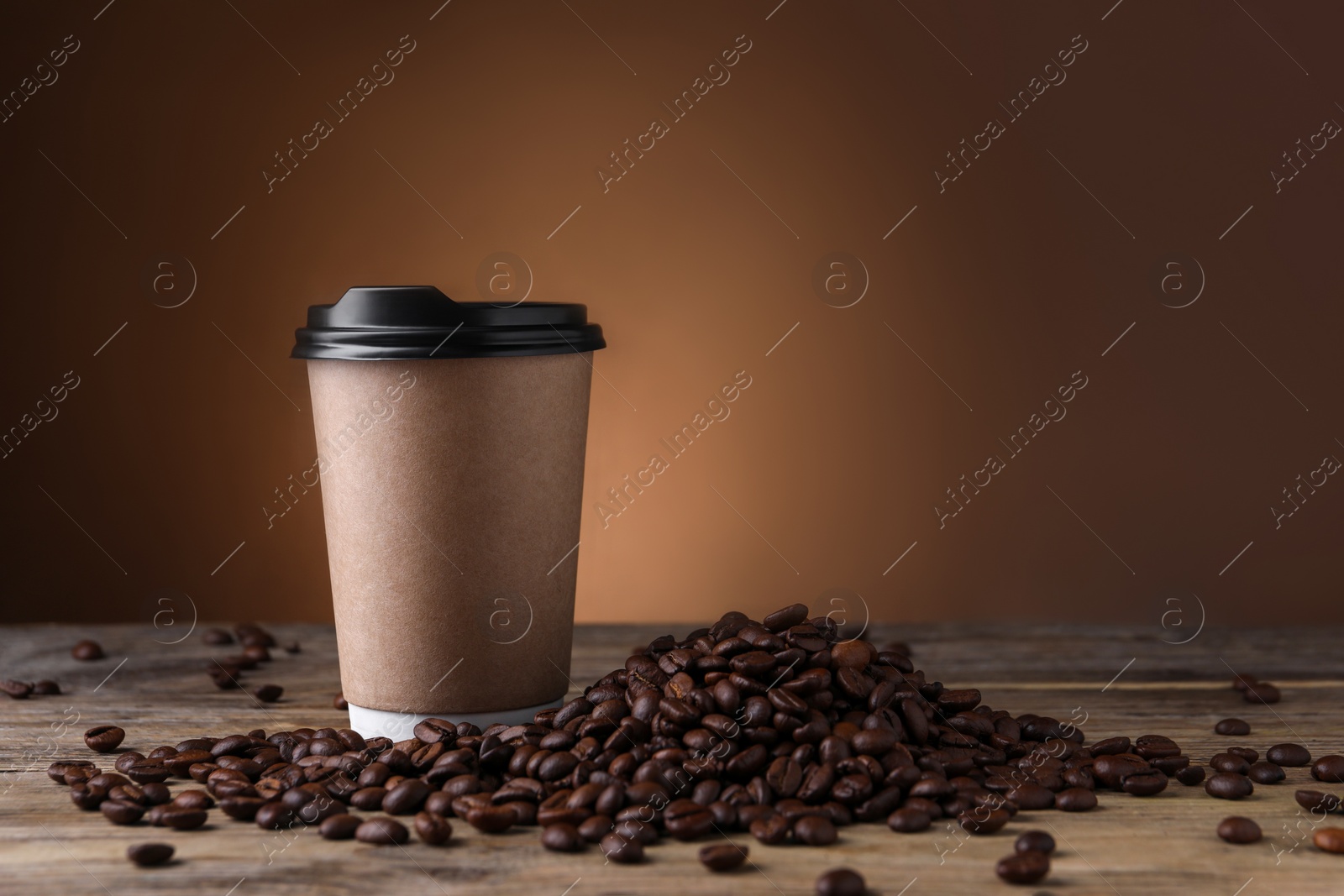 Photo of Coffee to go. Paper cup and roasted beans on wooden table, space for text