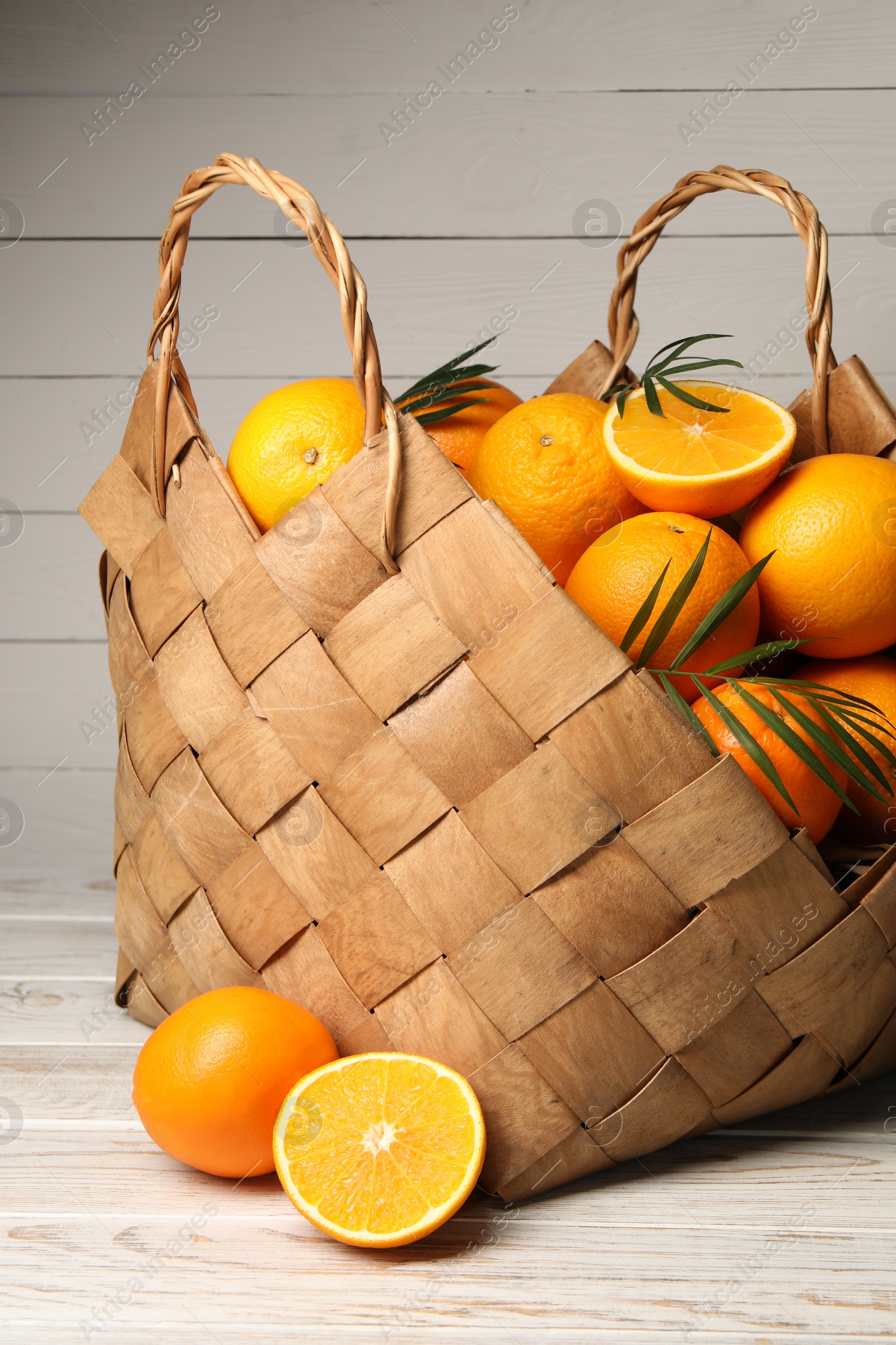 Photo of Many whole and cut oranges on white wooden table