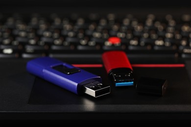 Photo of Modern usb flash drives on laptop, closeup