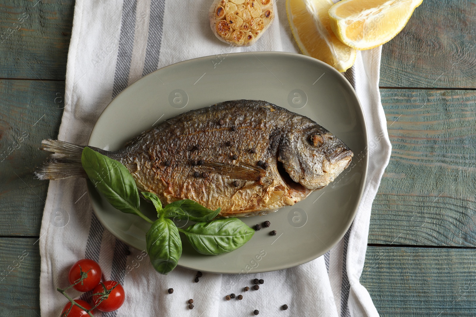 Photo of Delicious dorado fish with basil and spices served on wooden table, flat lay