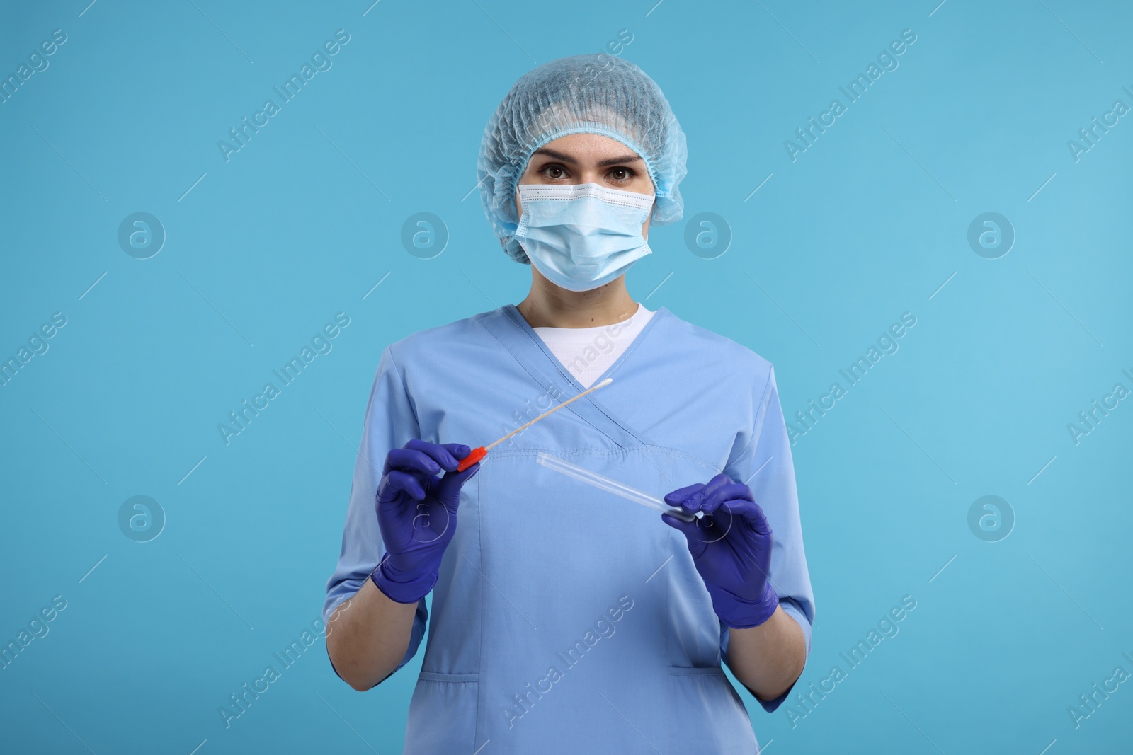 Photo of Laboratory testing. Doctor with cotton swab and tube on light blue background