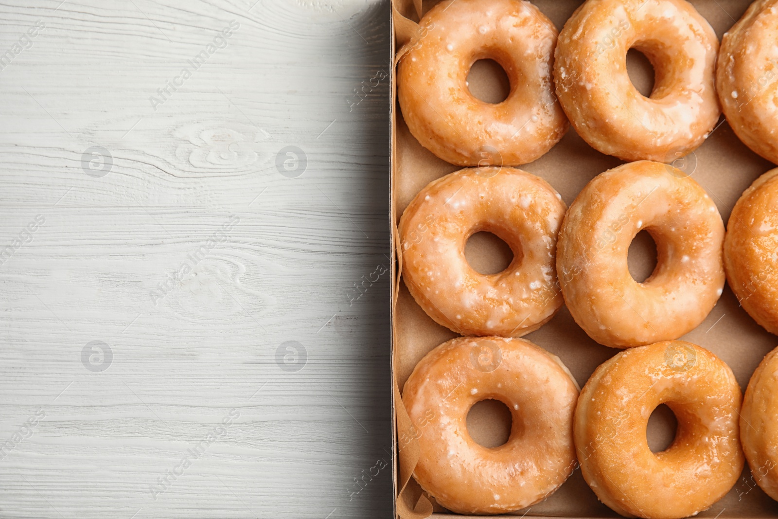 Photo of Delicious donuts on white wooden table, top view. Space for text