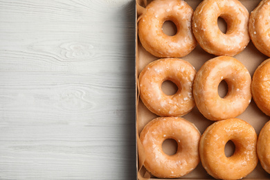 Delicious donuts on white wooden table, top view. Space for text