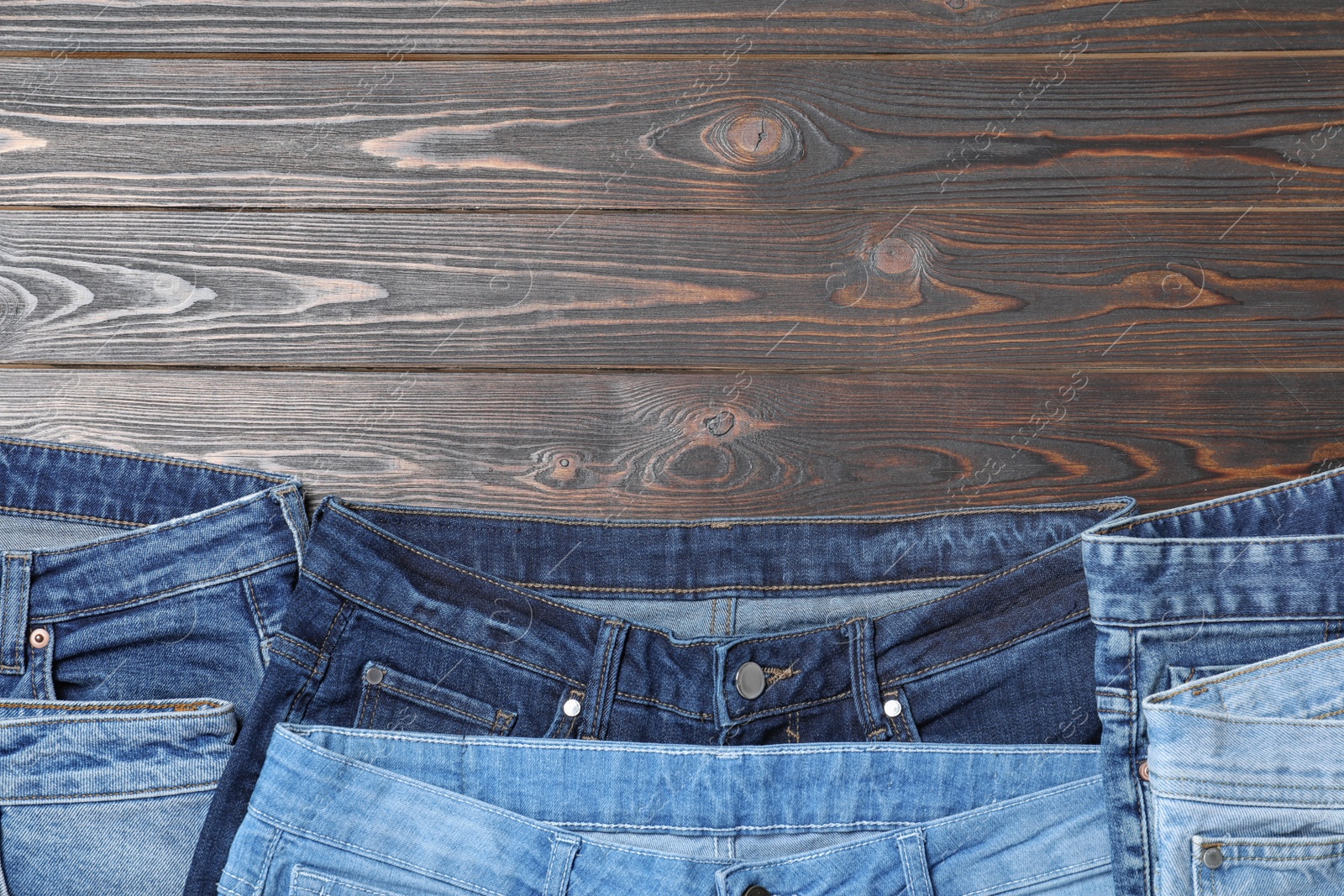 Photo of Collection of stylish jeans on wooden background, flat lay. Space for text