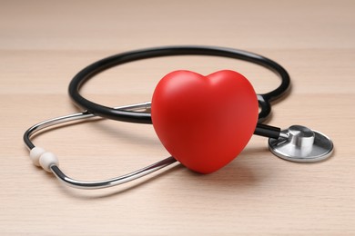 Photo of Stethoscope and red decorative heart on wooden background. Cardiology concept
