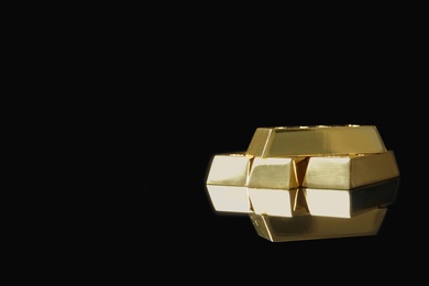 Photo of Shiny gold bars on black background. Space for text