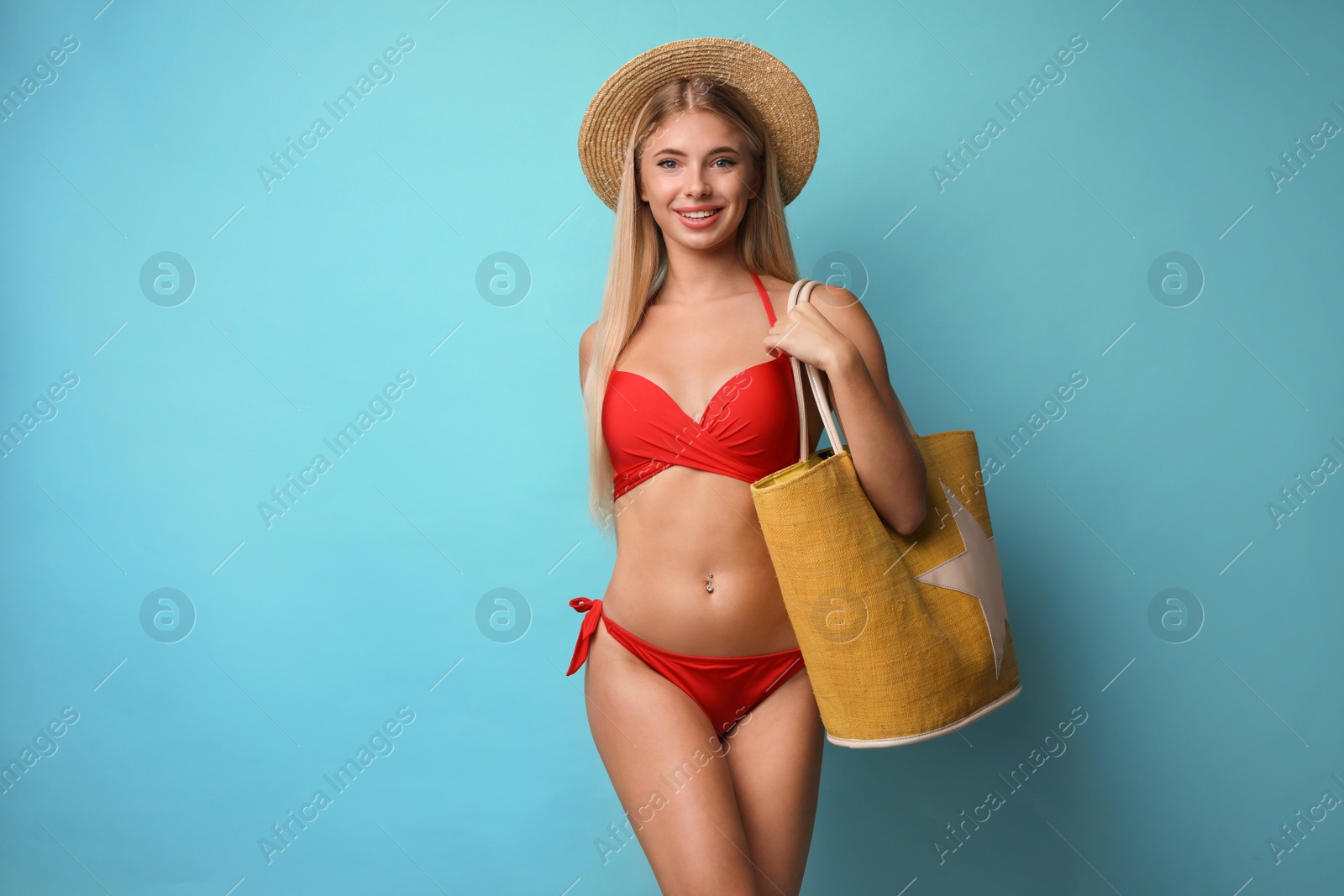 Photo of Pretty young woman wearing stylish bikini with bag on blue background
