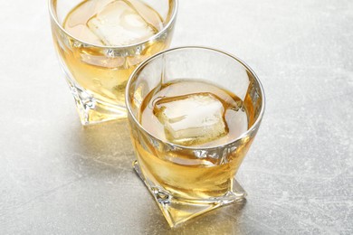Photo of Tasty whiskey in glasses on grey table, closeup