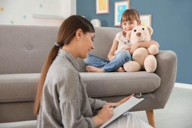 Photo of Female psychologist working with cute little girl in office