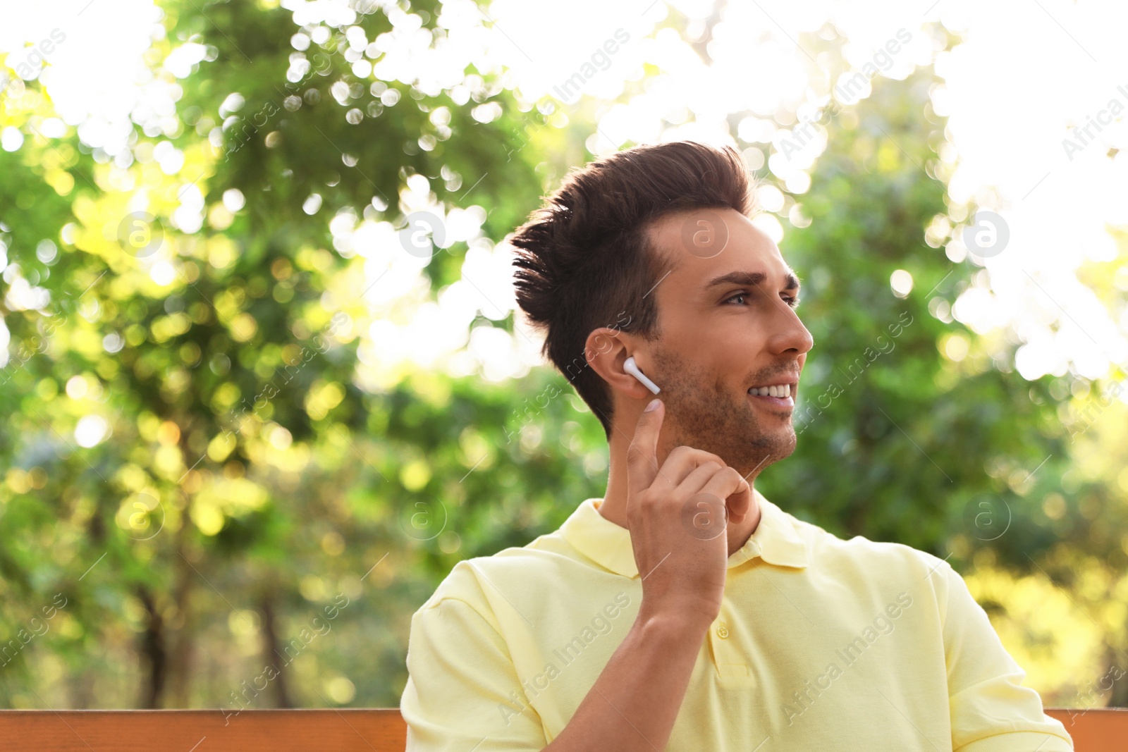 Photo of Young man with wireless earphones in park