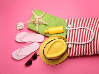 Photo of Stylish bag with beach accessories on pink background, flat lay