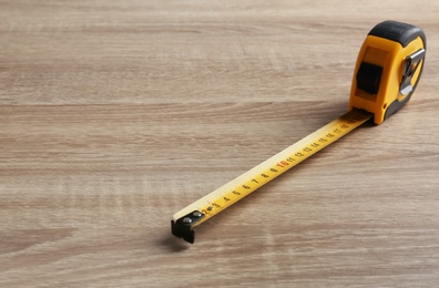 Metal measuring tape on wooden background. Space for text