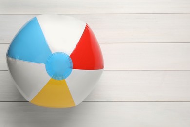 Photo of Colorful beach ball on white wooden background, top view. Space for text