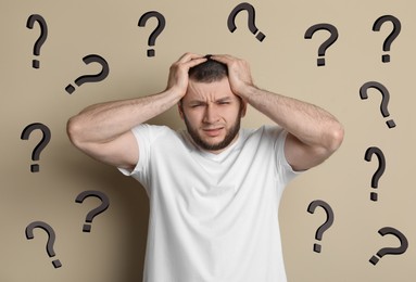 Amnesia. Confused man and question marks on beige background