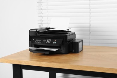 Photo of Modern printer with paper on wooden desk indoors
