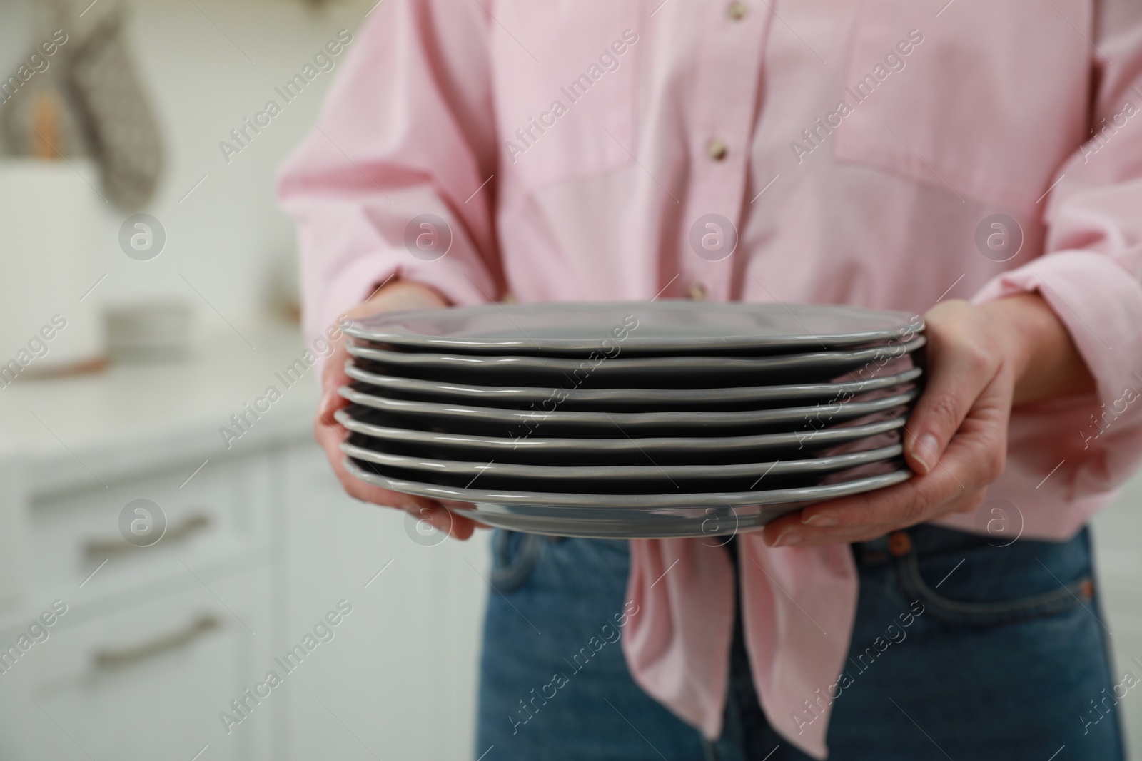 Photo of Woman holding plates in kitchen, closeup view