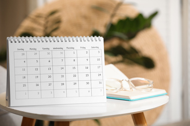 Photo of Paper calendar, notebook and glasses on white table indoors