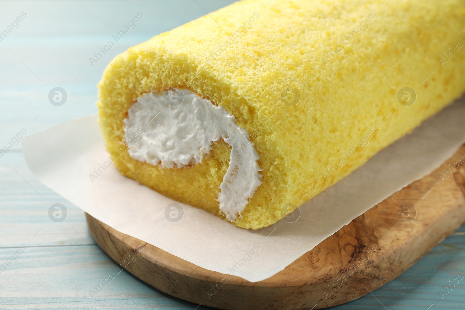 Photo of Delicious cake roll on light blue wooden table, closeup