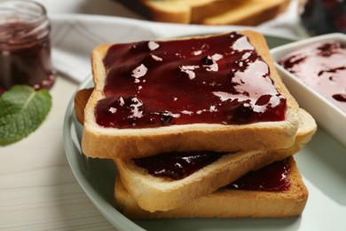 Photo of Delicious toasts with jam served on white wooden table, closeup