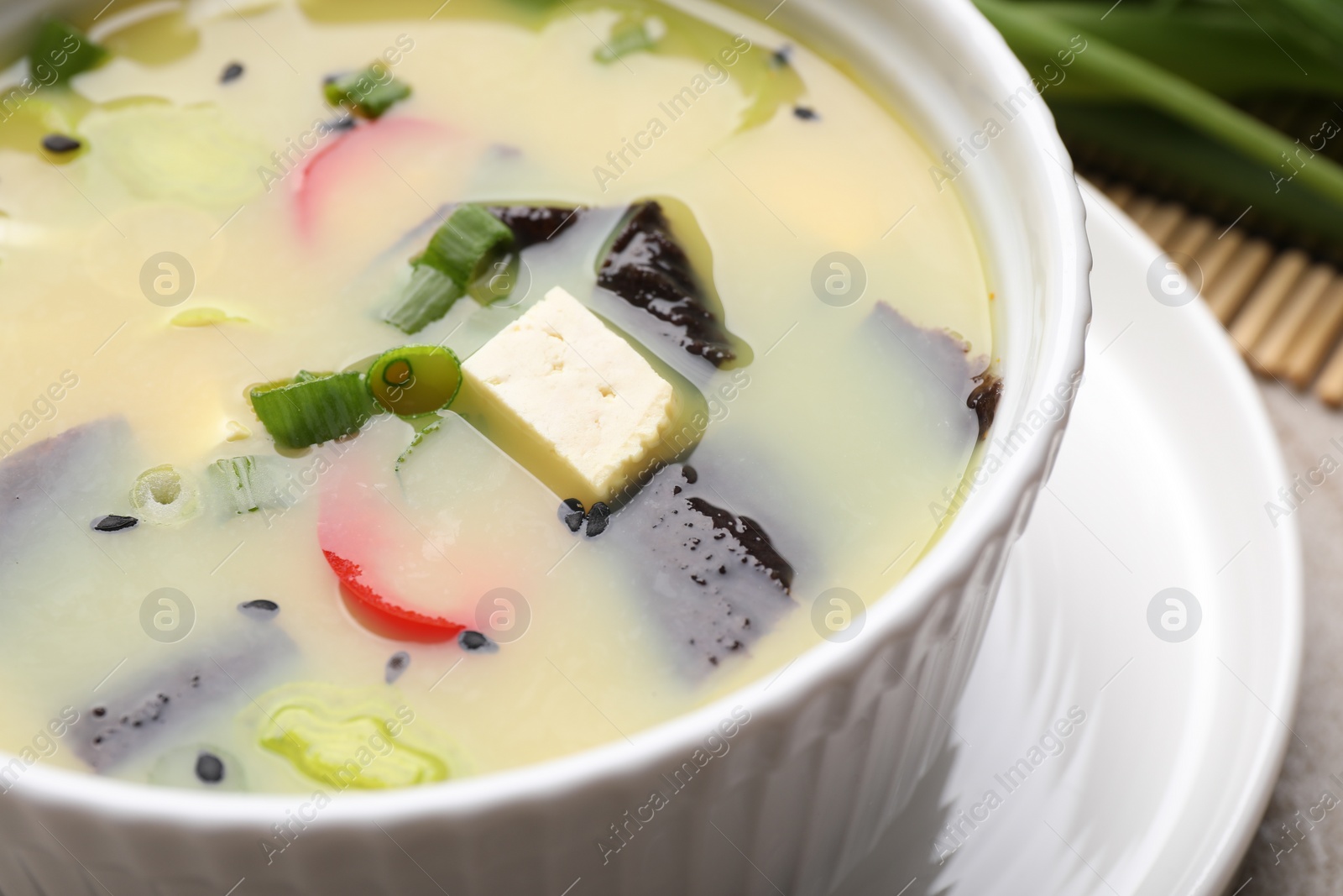 Photo of Bowl of delicious miso soup with tofu on table, closeup