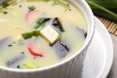 Photo of Bowl of delicious miso soup with tofu on table, closeup