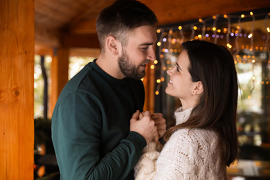 Happy couple in warm clothes on open terrace. Winter vacation