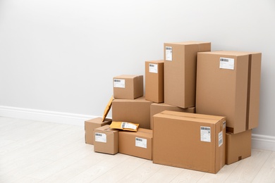 Photo of Stacked parcel boxes on floor against light wall