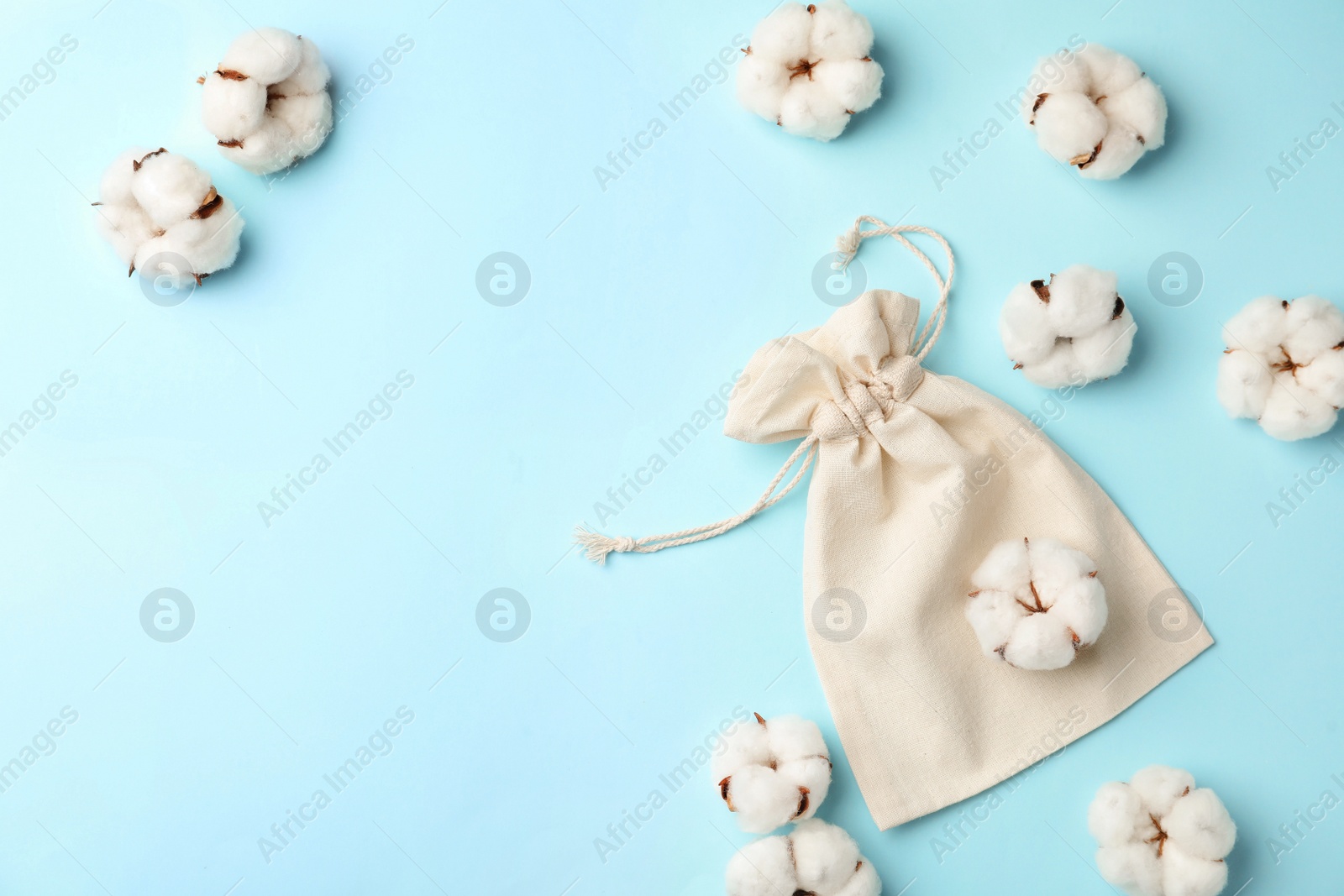 Photo of Cotton eco bag and flowers on light blue background, flat lay. Space for text