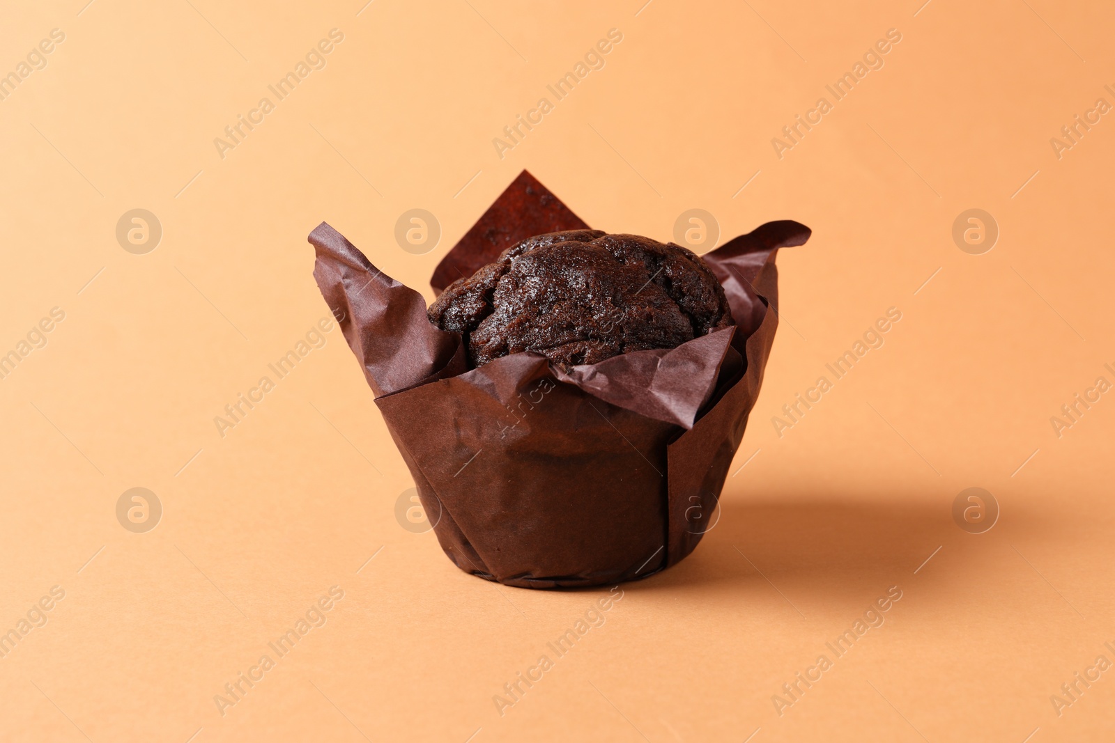 Photo of One tasty chocolate muffin on pale orange background