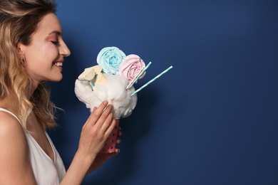 Photo of Young woman holding cotton candy dessert on blue background. Space for text