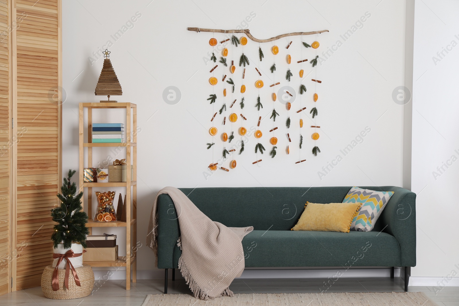 Photo of Stylish room interior with sofa and handmade dry orange decor