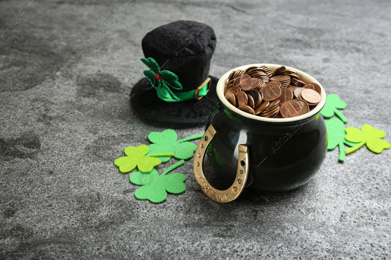 Photo of Composition with pot of gold coins and clover leaves on grey stone table. St. Patrick's Day celebration