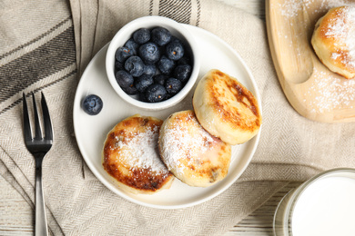 Photo of Delicious cottage cheese pancakes with blueberries and sugar powder on table, flat lay