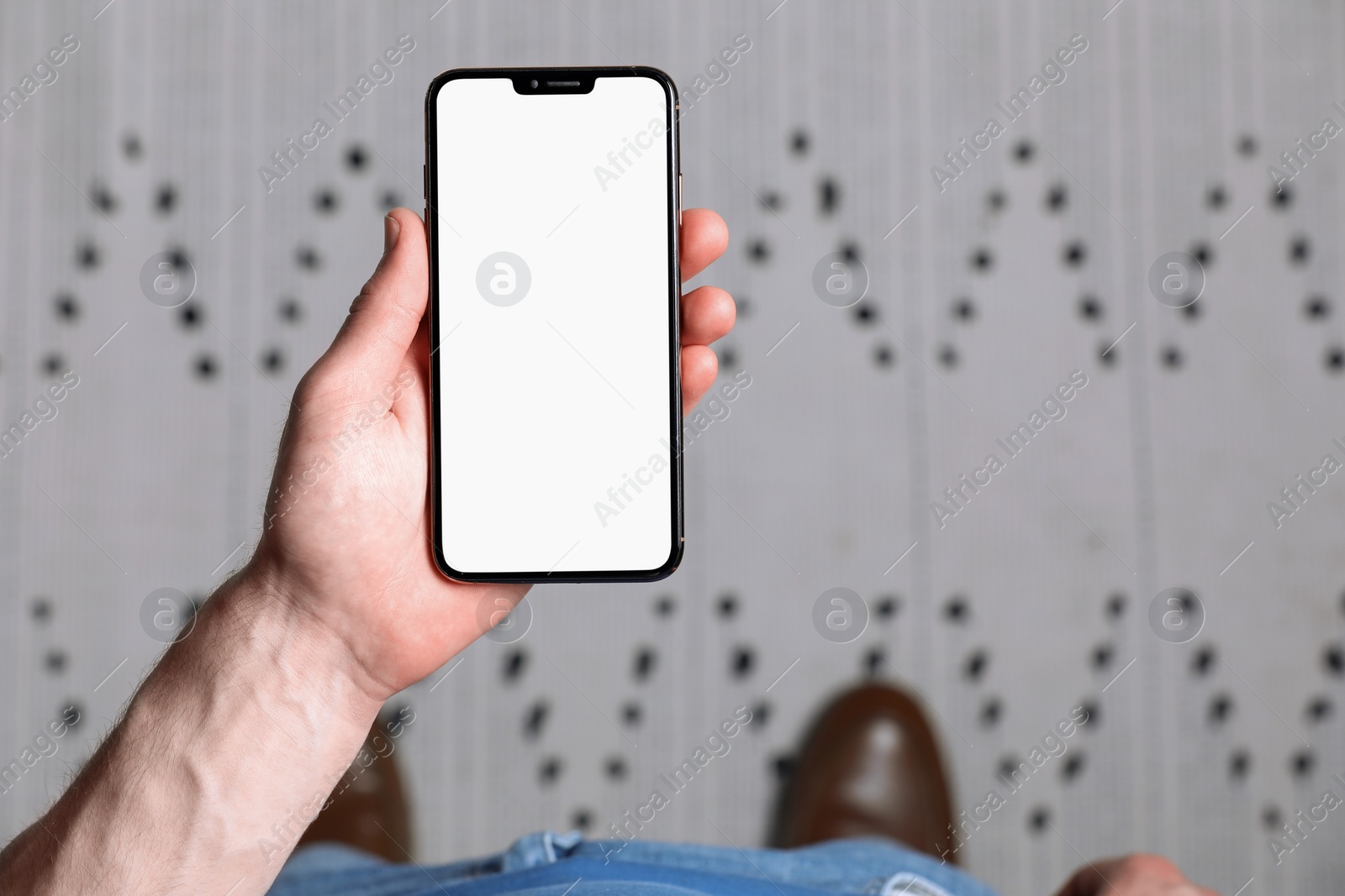 Photo of Man holding smartphone with blank screen indoors, top view. Mockup for design