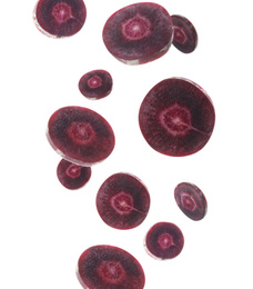 Purple carrot slices falling on white background