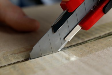 Photo of Man using utility knife to open parcel, closeup