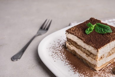 Photo of Plate of tiramisu cake on grey table, space for text