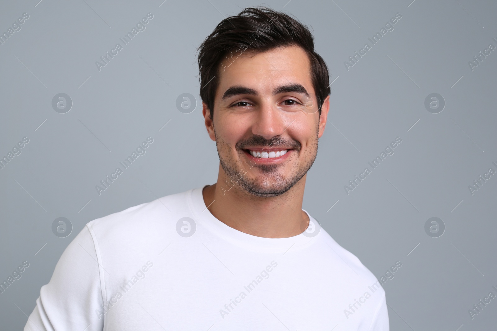 Photo of Portrait of handsome young man in white t-shirt on grey background
