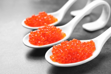 Photo of Spoons with delicious red caviar on table