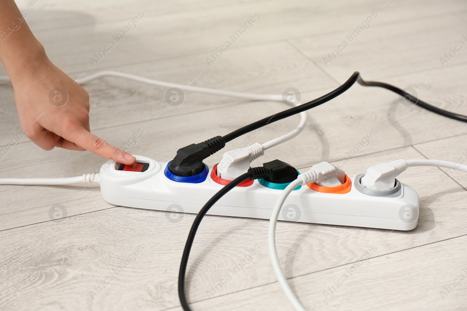 Photo of Woman pressing power button of extension cord on floor, closeup. Electrician's professional equipment