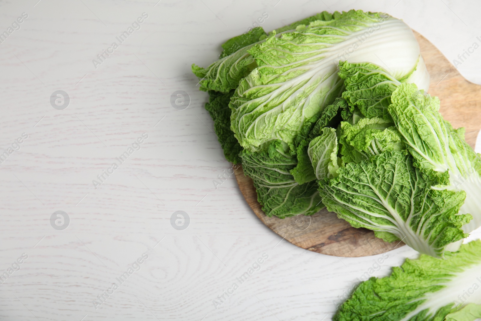 Photo of Fresh ripe Chinese cabbages on white wooden table, top view. Space for text